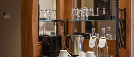 Una estación de café con cafetera, tazas y tetera.