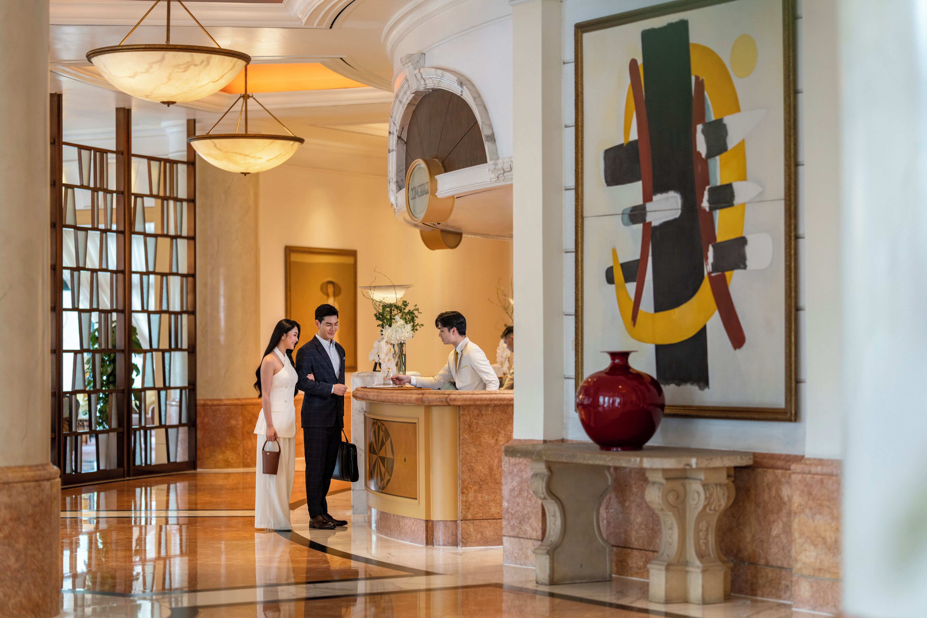 A lobby with a reception desk, a large abstract painting, and a decorative vase.