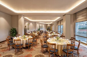 Une grande salle de banquet avec des tables rondes, des chaises et un sol recouvert de moquette.