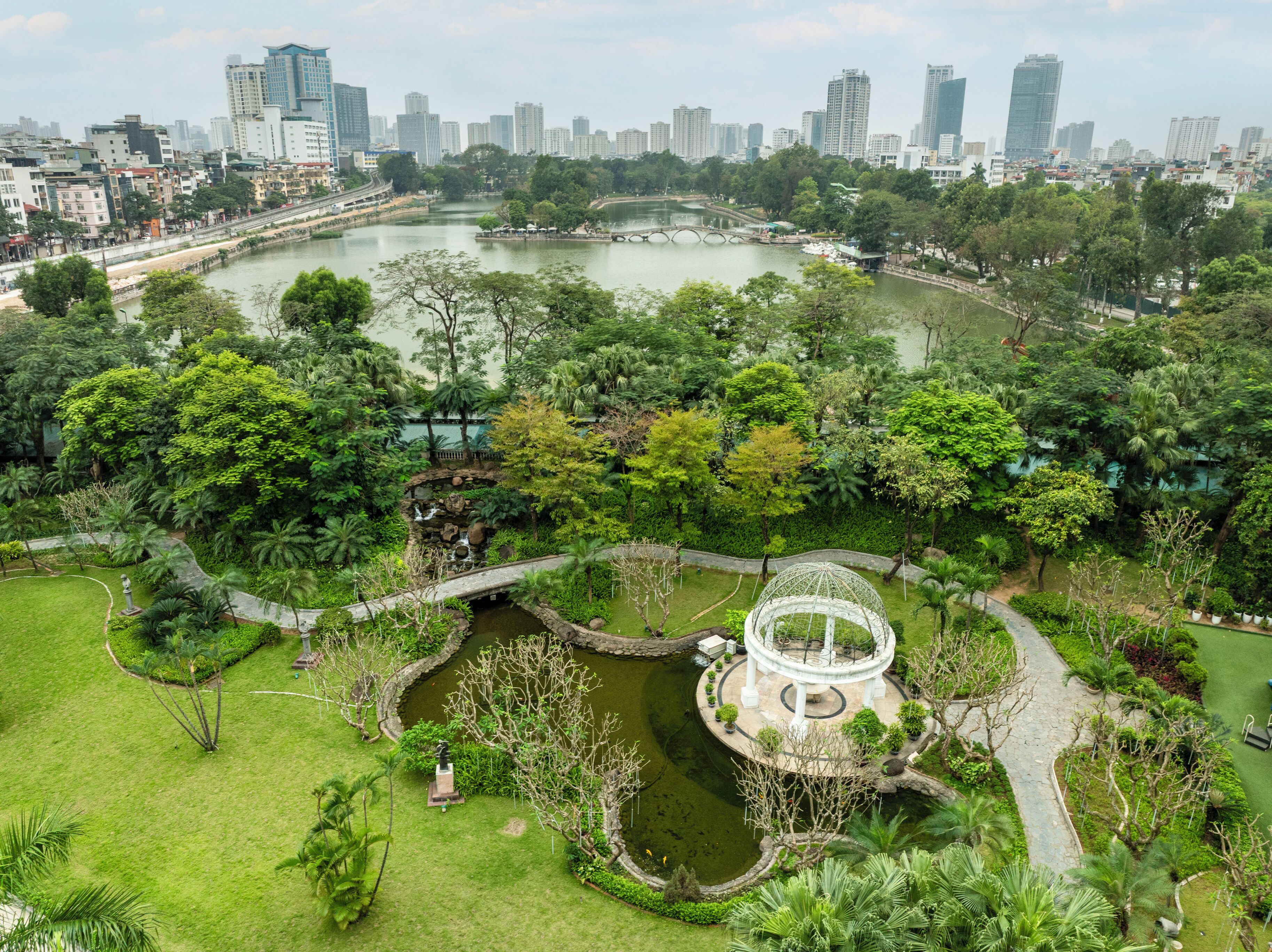 Un parc avec un étang, un pont et un kiosque.