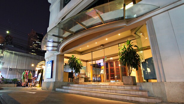 A modern hotel entrance with a glass facade, outdoor seating area, and potted plants. - Le Siam Hotel Silom Bangkok by PCL (Bangkok)