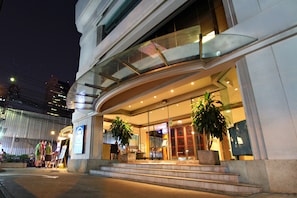A modern hotel entrance with a glass facade, outdoor seating area, and potted plants. - Le Siam Hotel Silom Bangkok by PCL (Bangkok)