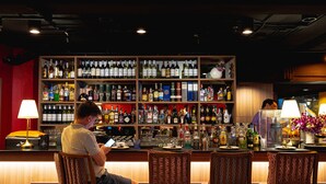 A bar area with multiple shelves of liquor bottles, a counter, and bar stools. - Le Siam Hotel Silom Bangkok by PCL (Bangkok)