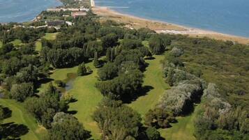 An aerial view of a golf course with a beach and ocean in the background.