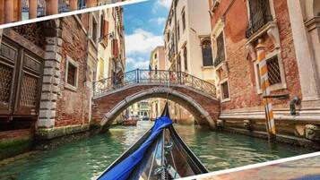 A canal with a bridge and buildings on either side, a gondola on the water, and a sunset view of the city.