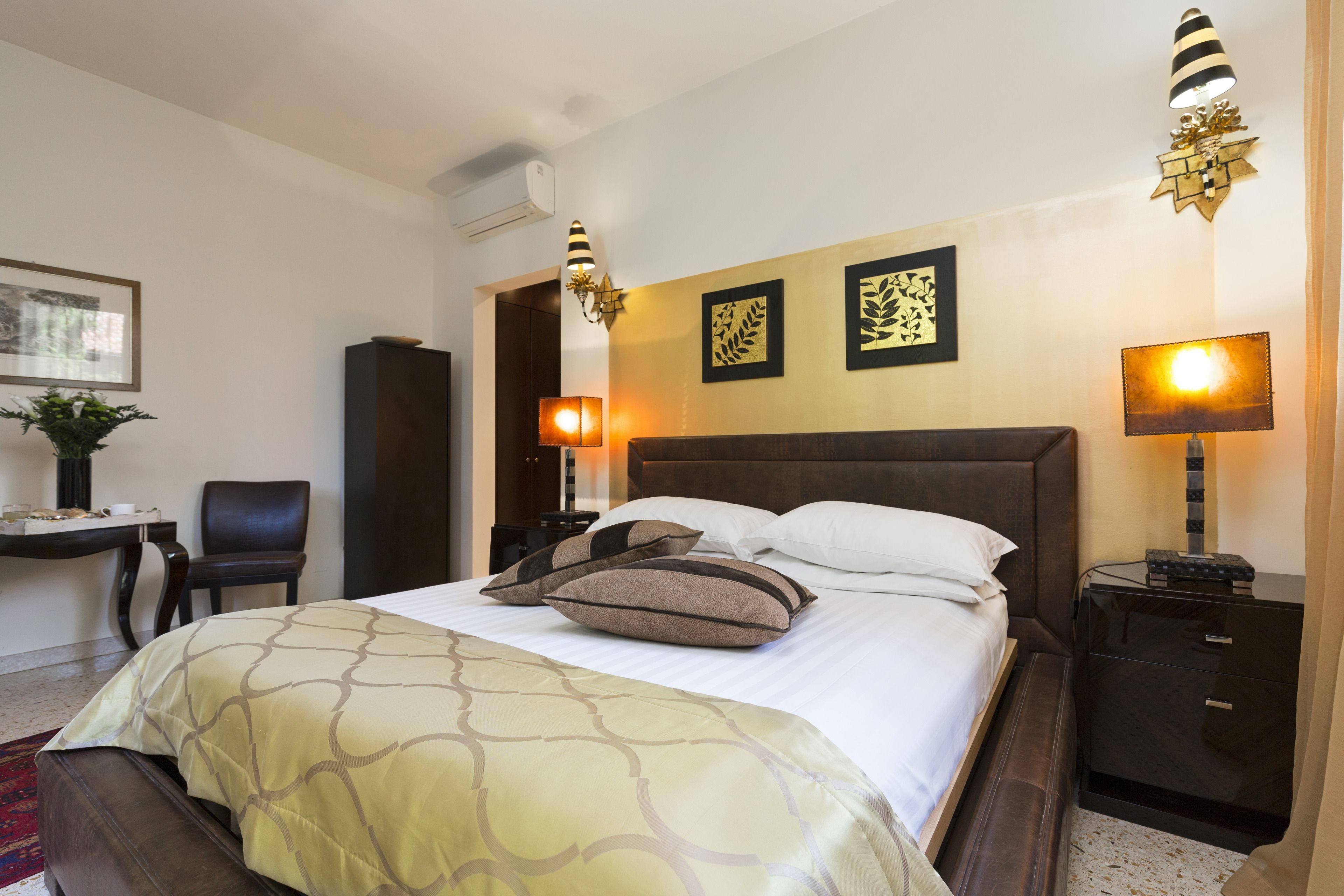 Una habitación de hotel con cama, mesitas de noche, escritorio, silla y cuadros en la pared.