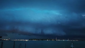 A nighttime view of a coastal area with a dark sky and distant city lights.