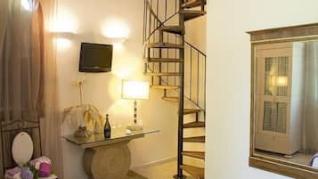 Une chambre à coucher avec un lit, une petite table avec une lampe, une télévision, un escalier et une fenêtre avec des rideaux.