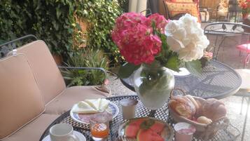 Un tavolo rotondo apparecchiato per la colazione, con piatti, tazze e un vaso di fiori.