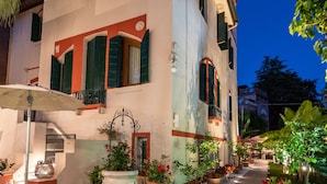 A two-story building with a balcony, potted plants, and a gravel pathway. - Hotel Villa Stella.check-in.9AM-3PM (Venice)