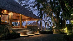 A thatched-roof structure with outdoor seating and steps leading to a covered area.