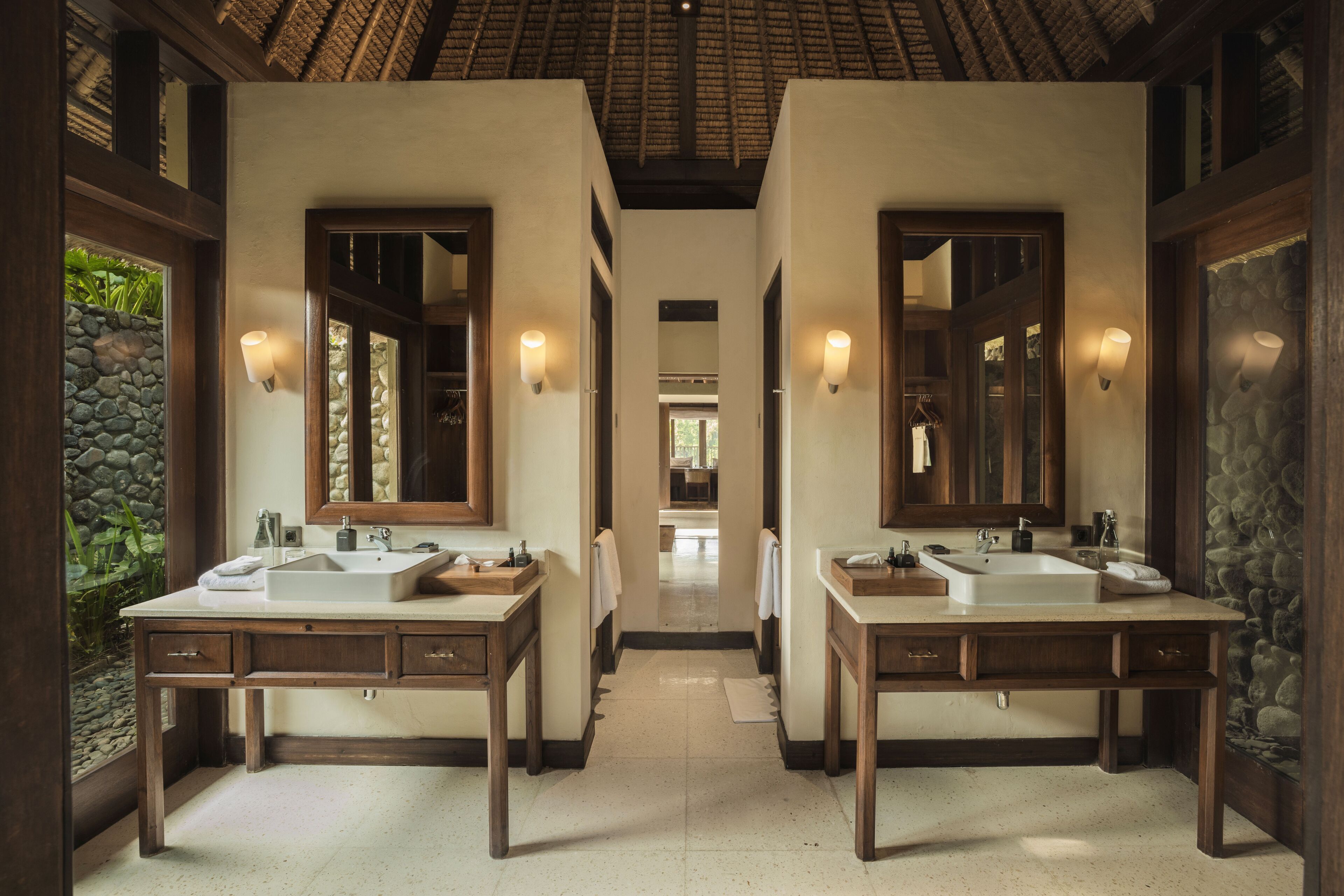 A luxurious bathroom with two sinks, large mirrors, and stone walls.