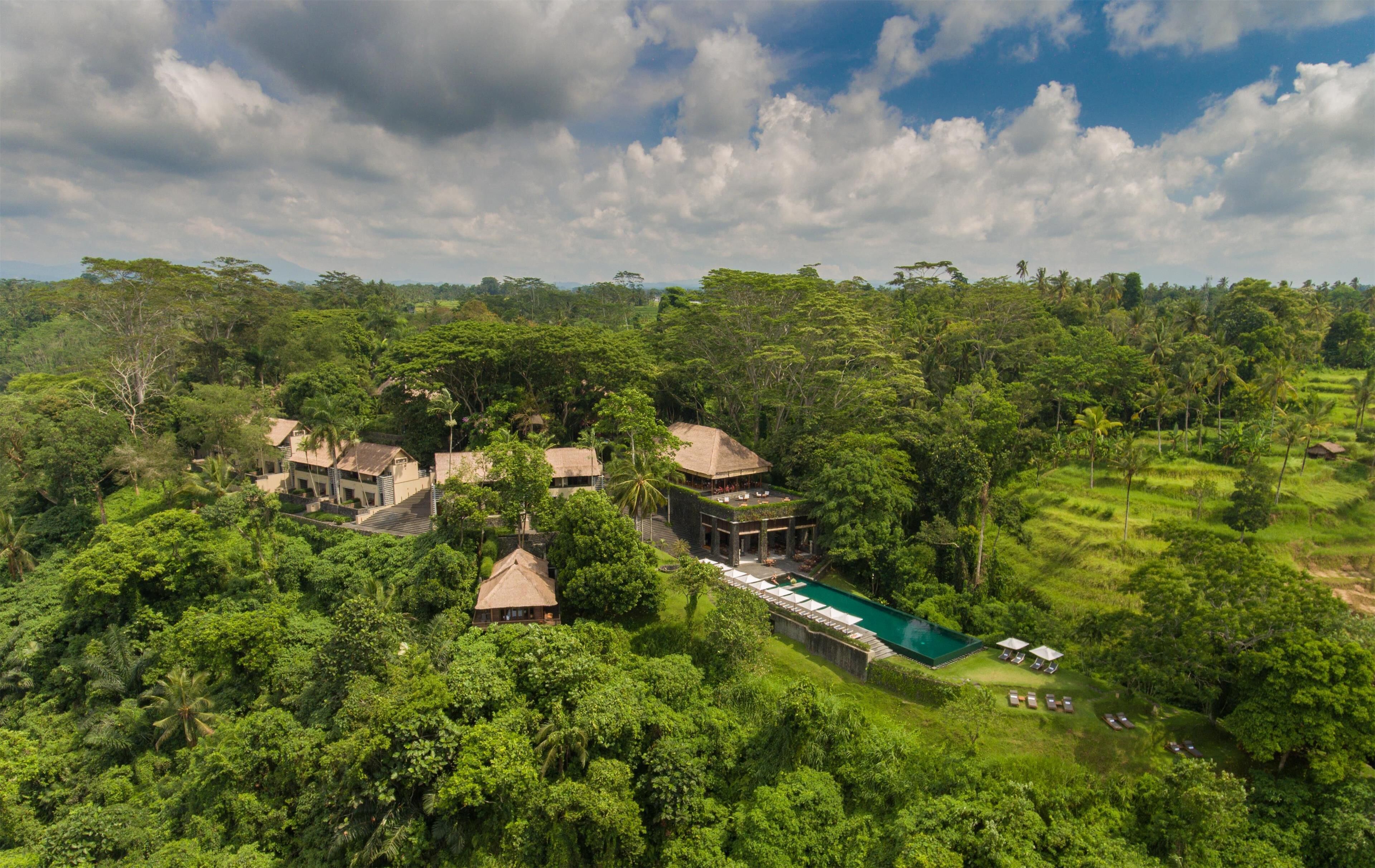 Ein Resort mit mehreren Gebäuden, umgeben von üppiger Vegetation, einem Swimmingpool und blauem Himmel.