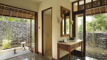 Une salle de bain avec un mur en pierre, un meuble-lavabo en bois et un grand miroir.