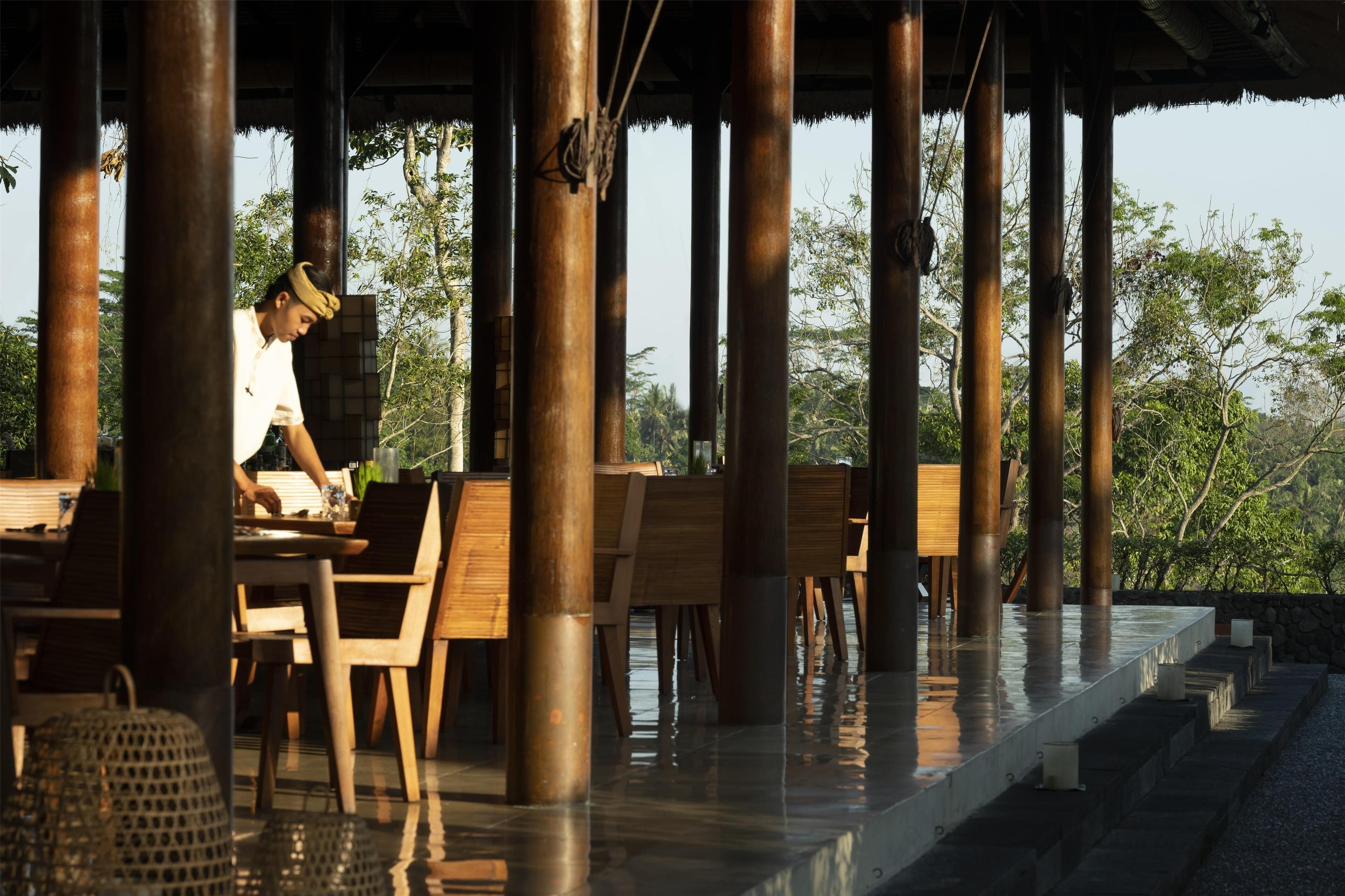 An outdoor dining area with wooden tables and chairs, surrounded by tall metal pillars.