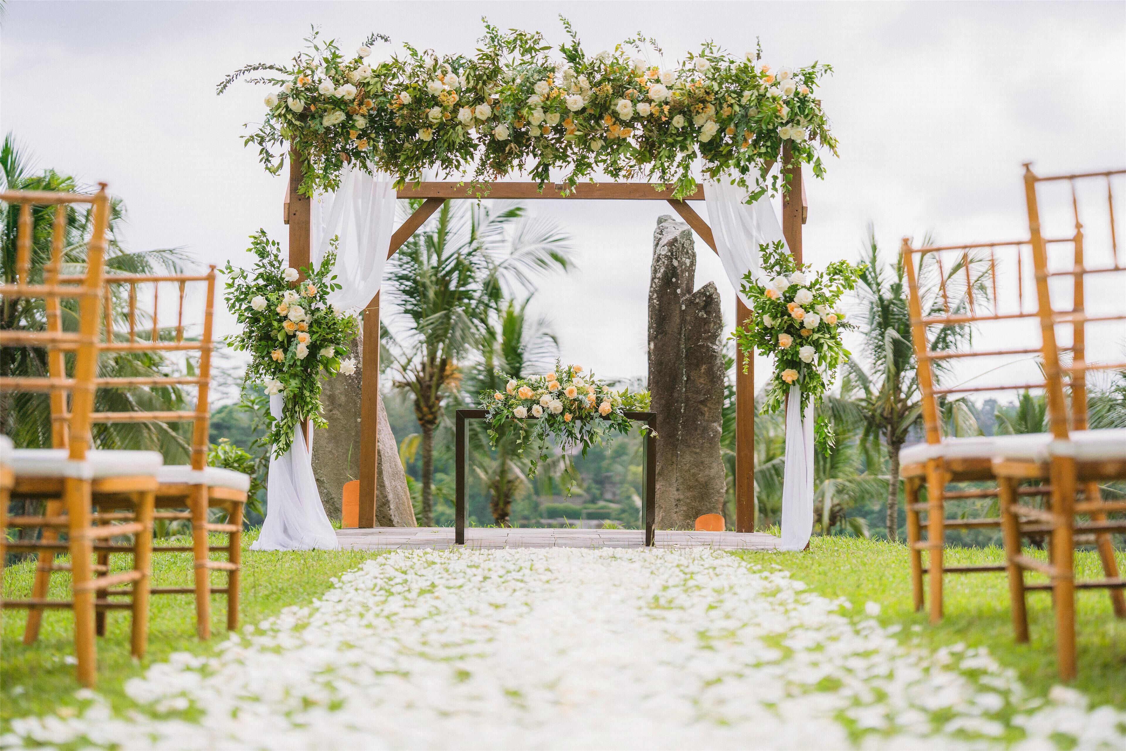 A wedding ceremony setup with a floral arch and chairs arranged on a grassy area.
