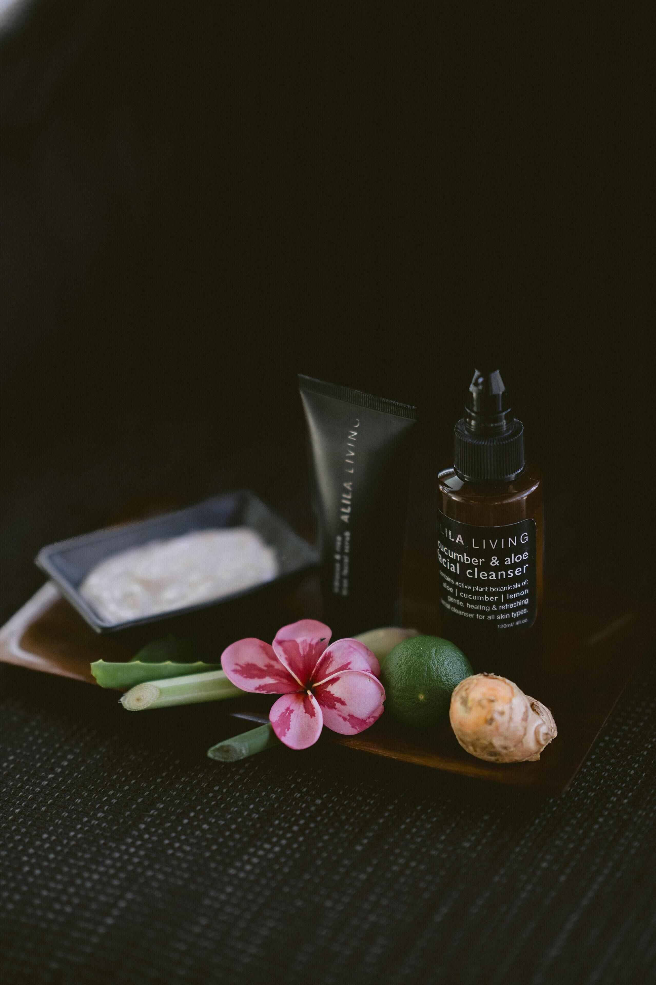 A skincare product, a small container, and a flower on a tray.