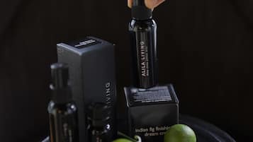 A hand holding a black spray bottle, surrounded by various black boxes and bottles on a black tray.
