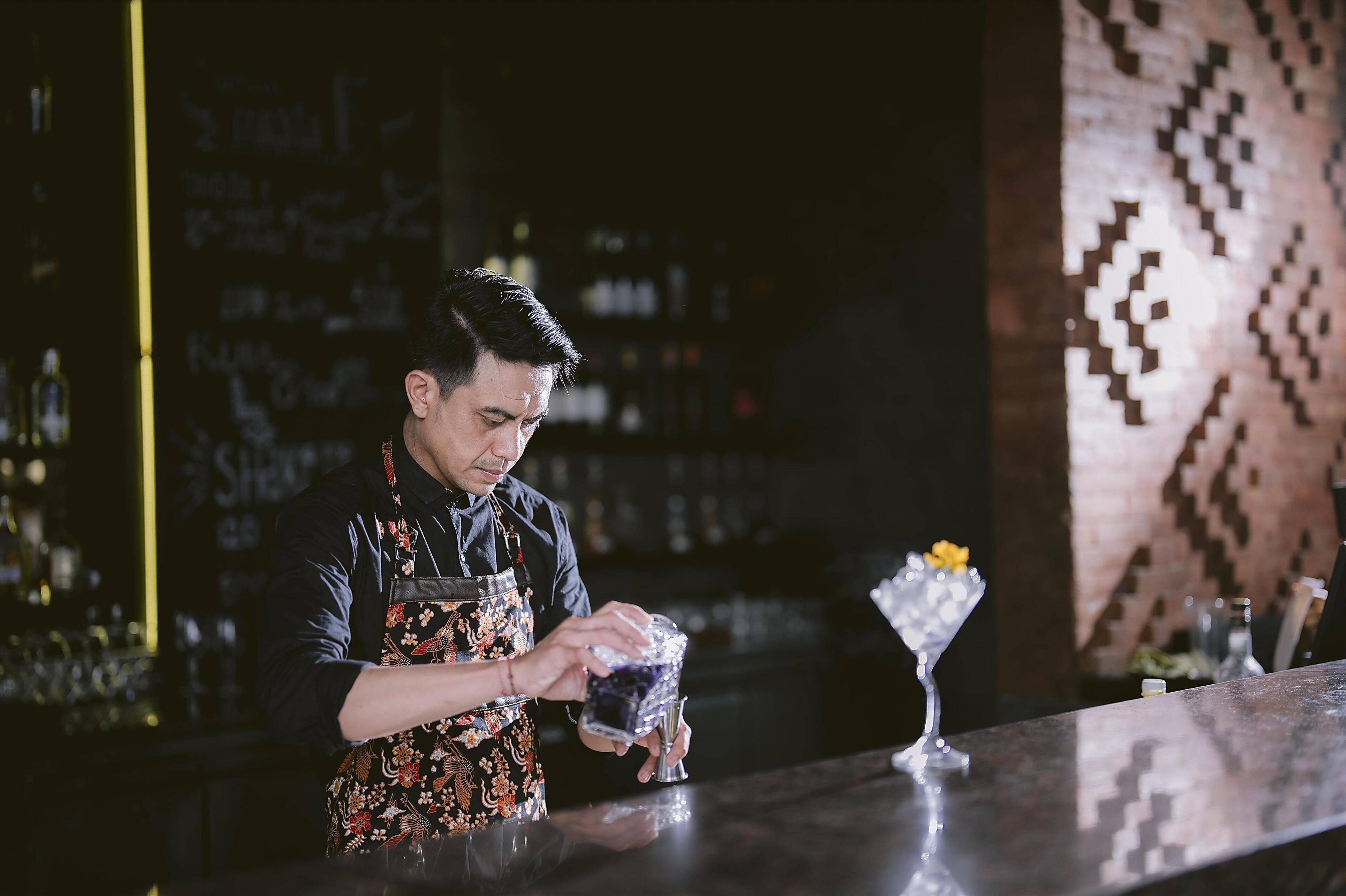 A bartender at a bar, preparing a drink.