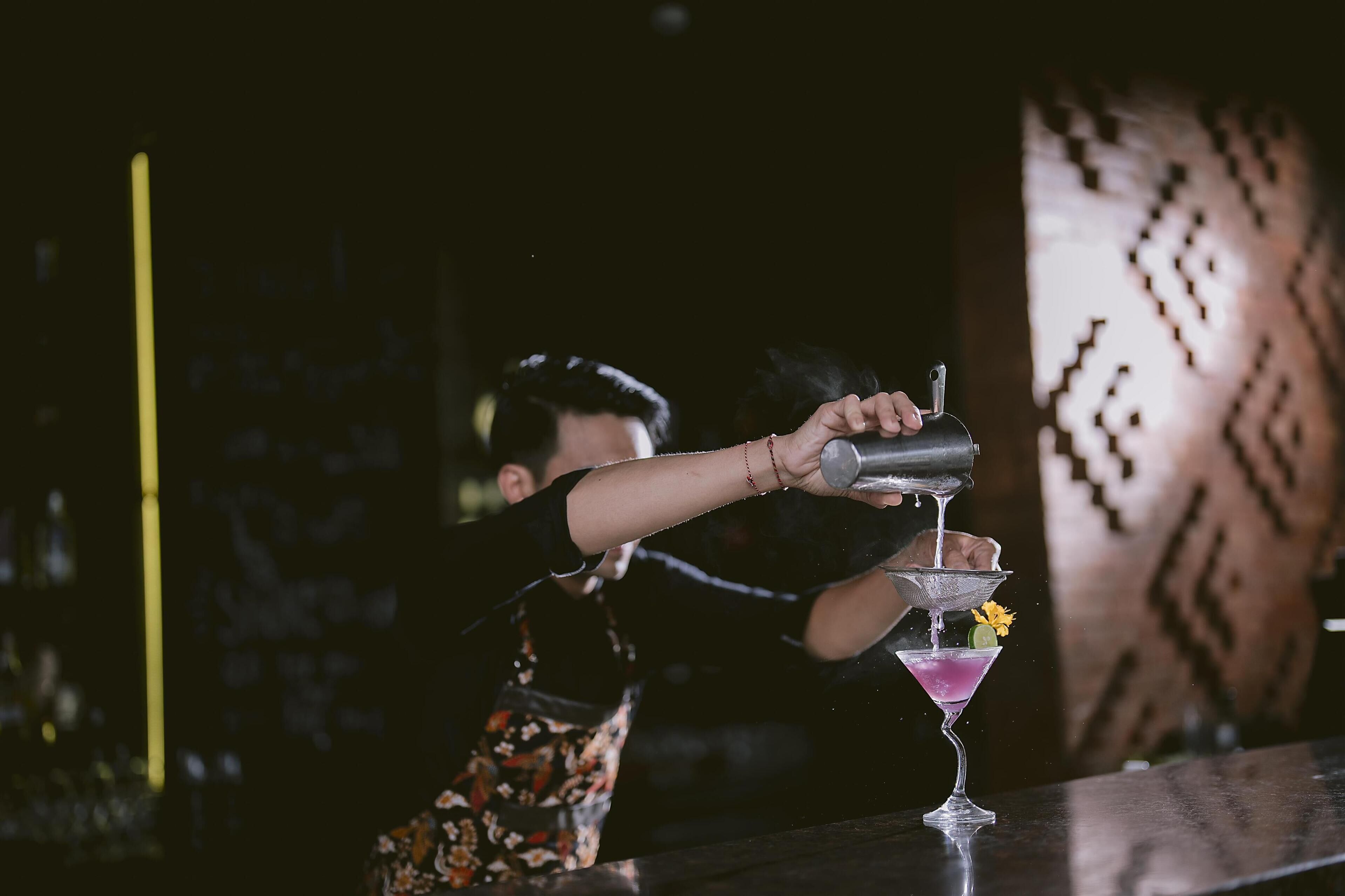 Un barman verse une boisson dans un verre à martini.