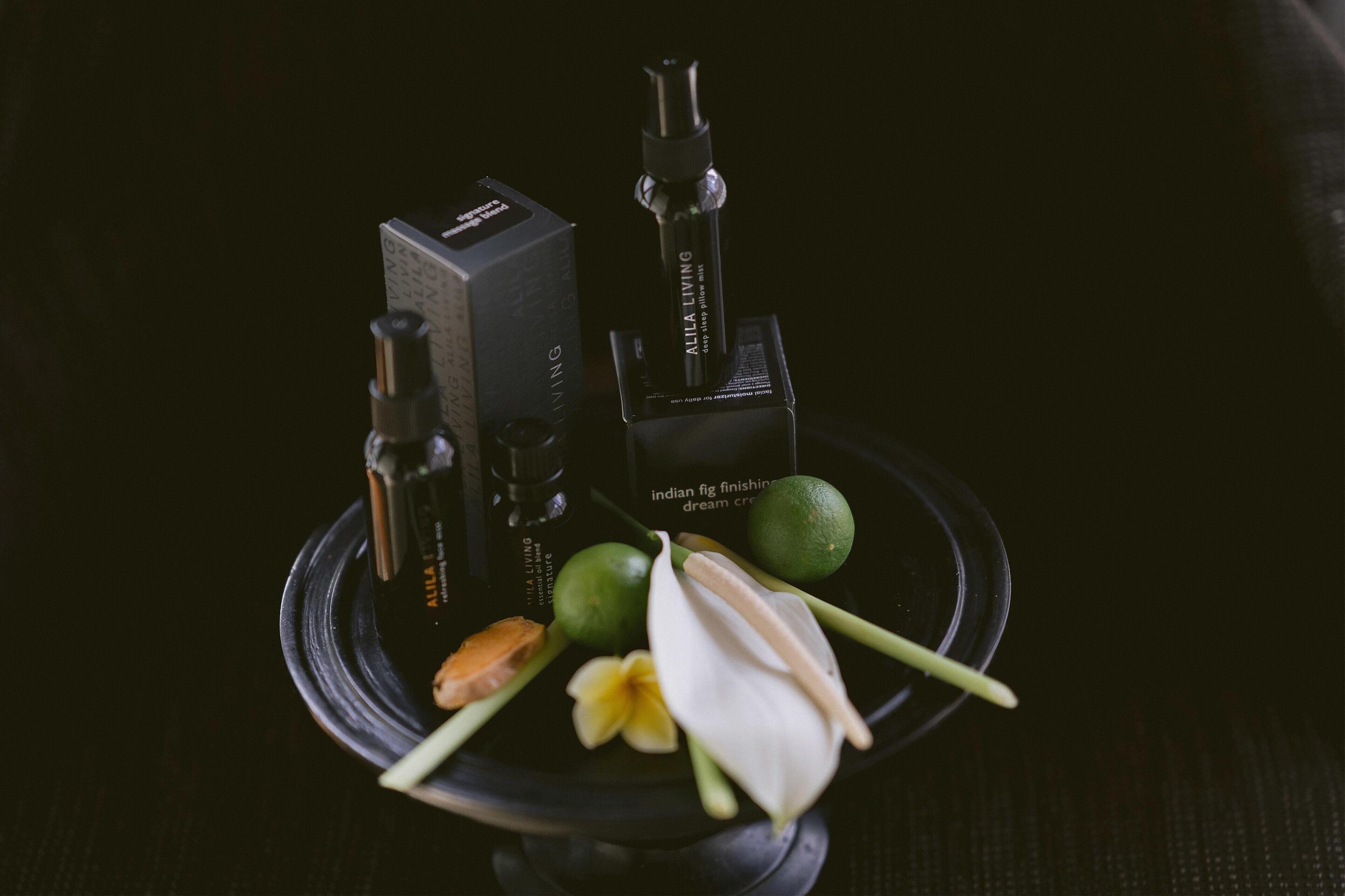 A black tray with a box, a bottle, a lime, a flower, and a leaf.