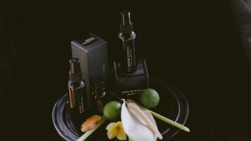 A black tray with a box, a bottle, a lime, a flower, and a leaf.