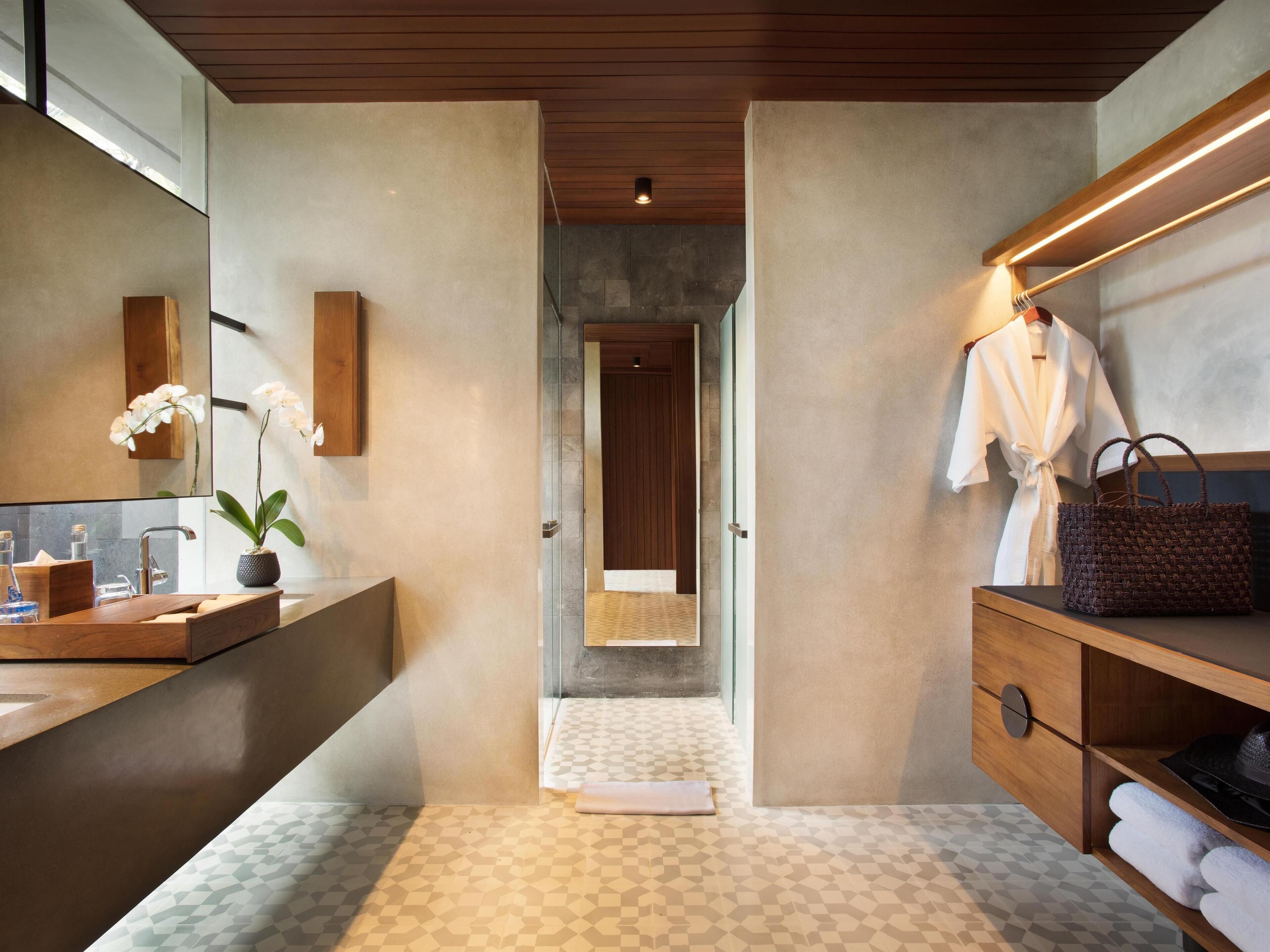 A modern bathroom with a large mirror, wooden vanity, and a towel rack.