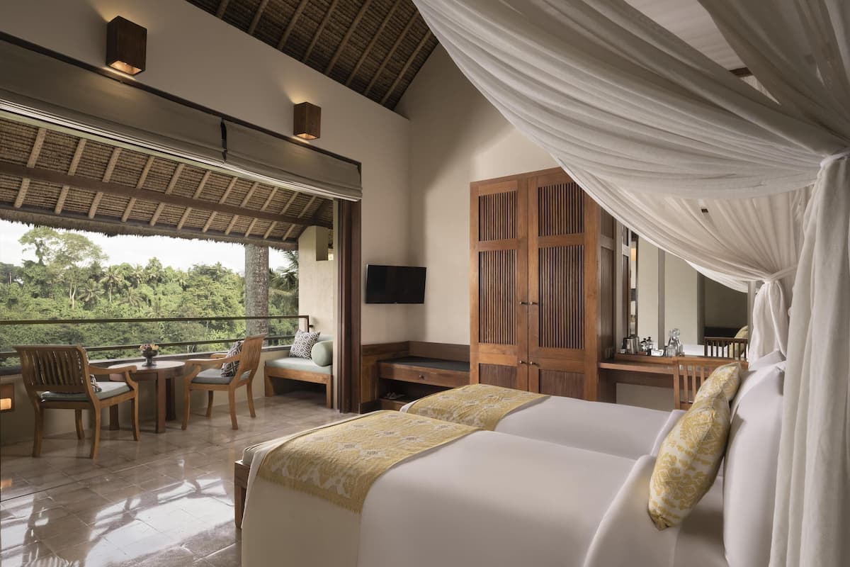 A bedroom with a bed, a desk, a chair, and a TV. There is a balcony with chairs and a table.