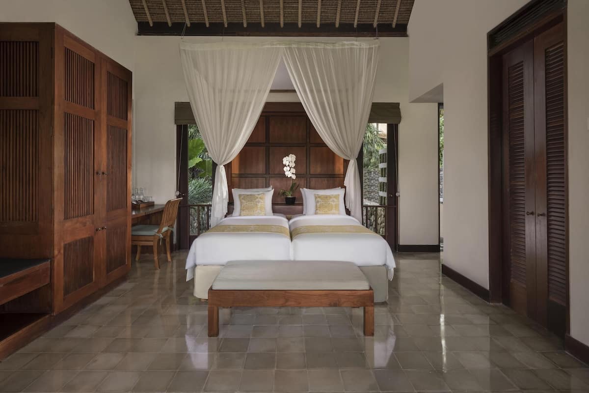 A bedroom with a large bed, a wooden bench, a desk, and a chair.