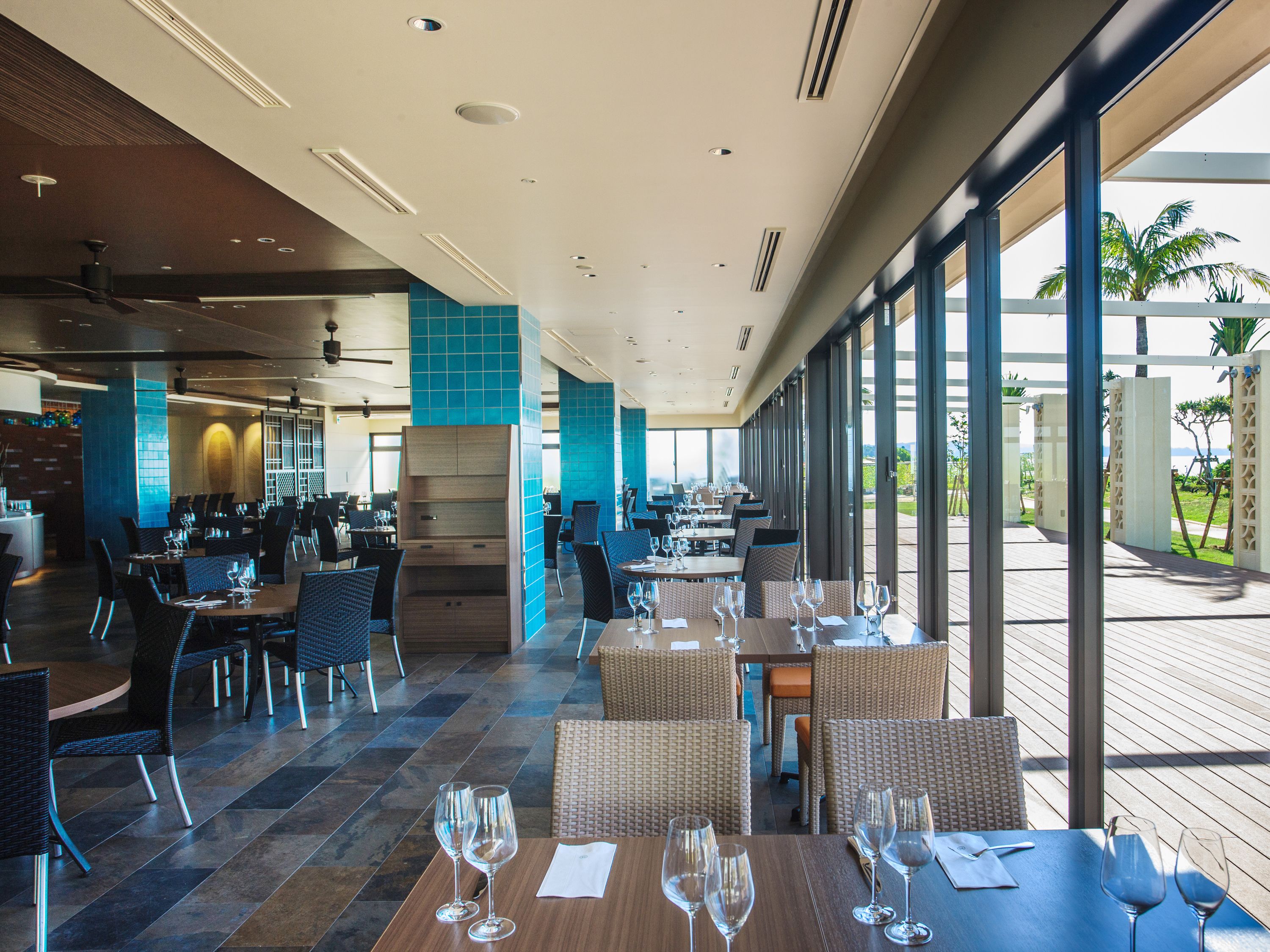 Een ruim restaurant met hoge plafonds, grote ramen en een gevarieerd aanbod aan zitplaatsen, waaronder tafels en stoelen.