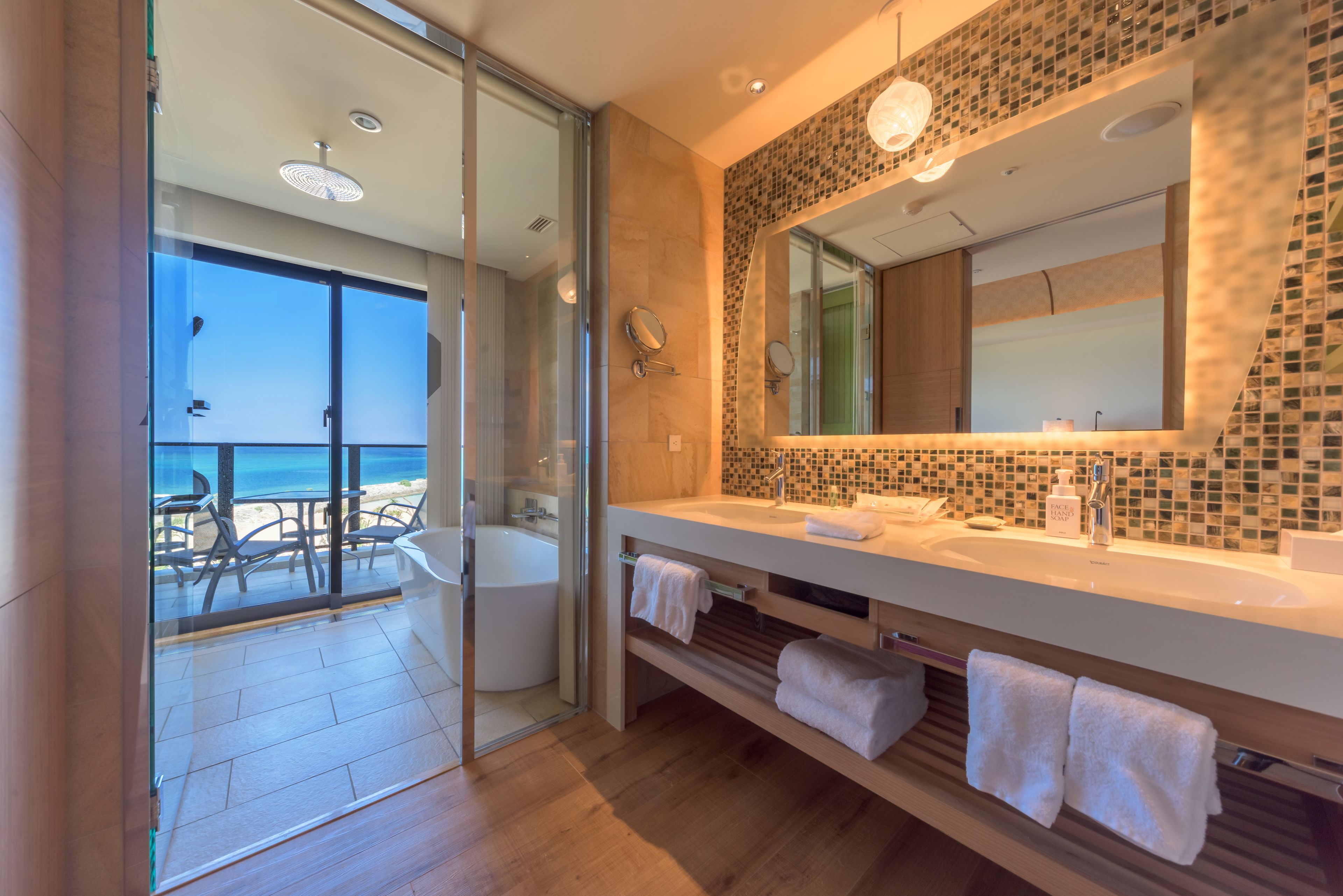A modern bathroom with a large mirror, two sinks, and a glass shower enclosure.