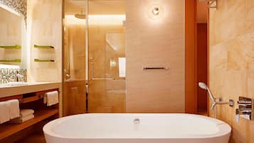 Ein modernes Badezimmer mit freistehender Badewanne, einer Glaskabine zur Dusche und einem Waschtisch mit Spiegel und Handtuchhaltern.
