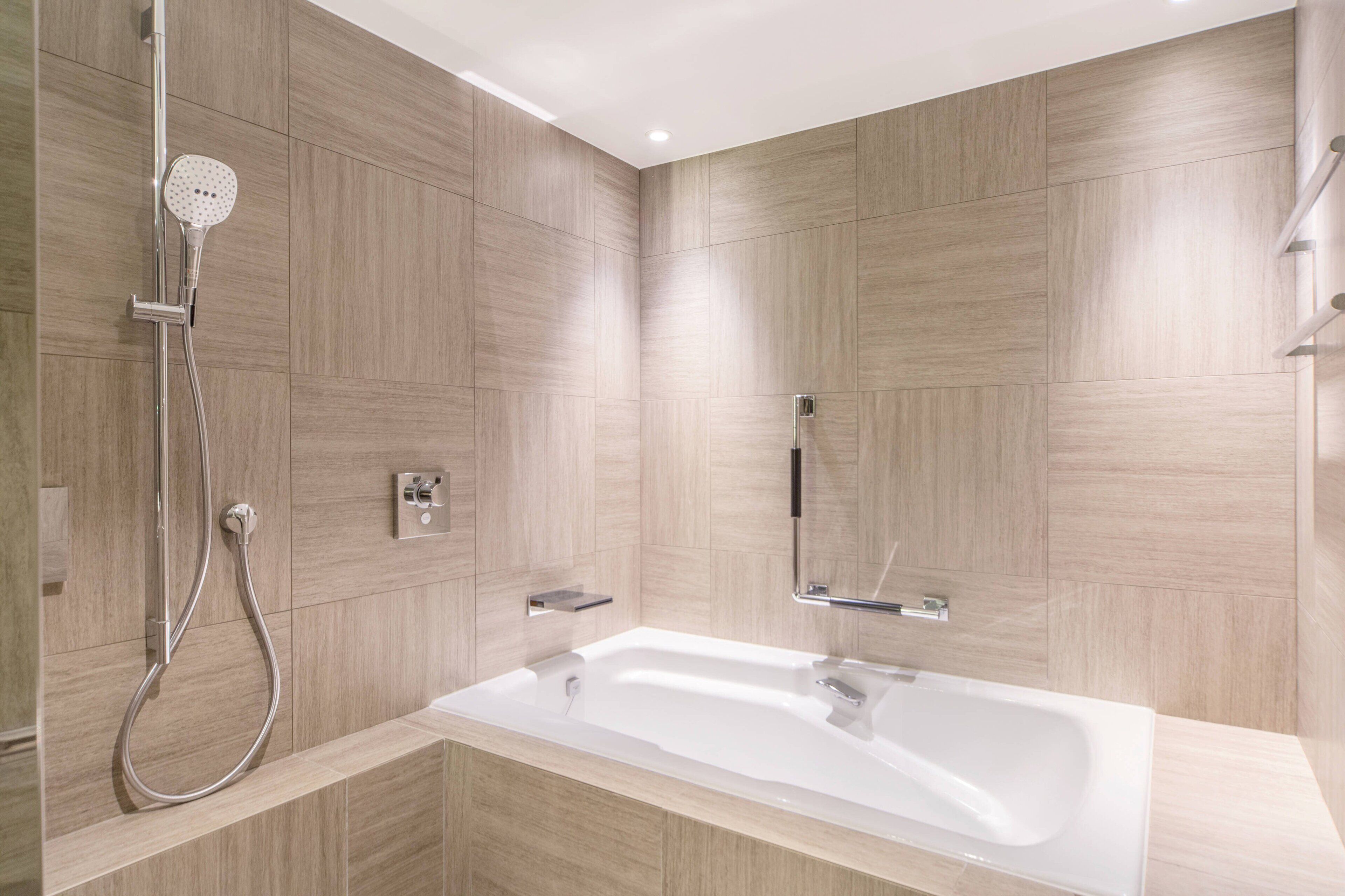 A modern bathroom with a freestanding bathtub, a handheld showerhead, and a wall-mounted towel rack.