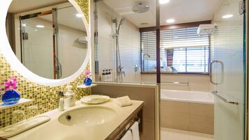 Une salle de bain moderne avec un grand miroir ovale, un lavabo, une douche et une baignoire.