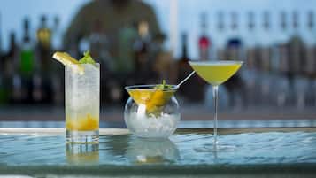 A bar setting with a tall glass and a martini glass on a reflective surface.
