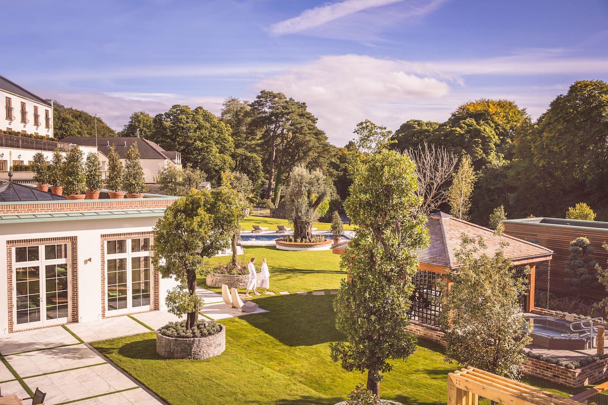 A courtyard with a swimming pool, a gazebo, and a building with large windows and a brick facade.