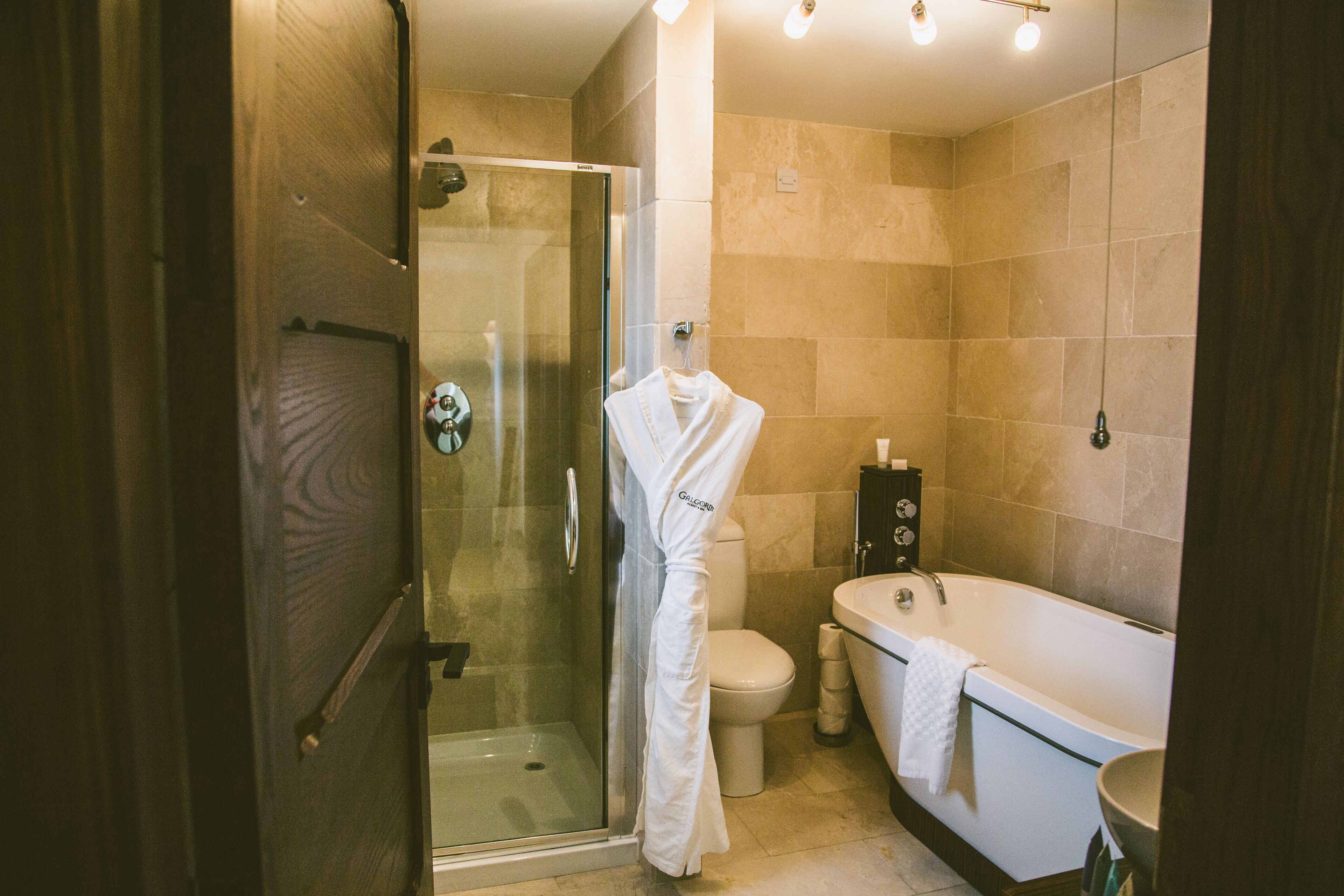 A modern bathroom with a glass-enclosed shower, a white toilet, and a freestanding bathtub.