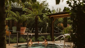 A wooden deck with a hot tub, surrounded by lush greenery and a pergola. - Galgorm (Ballymena)