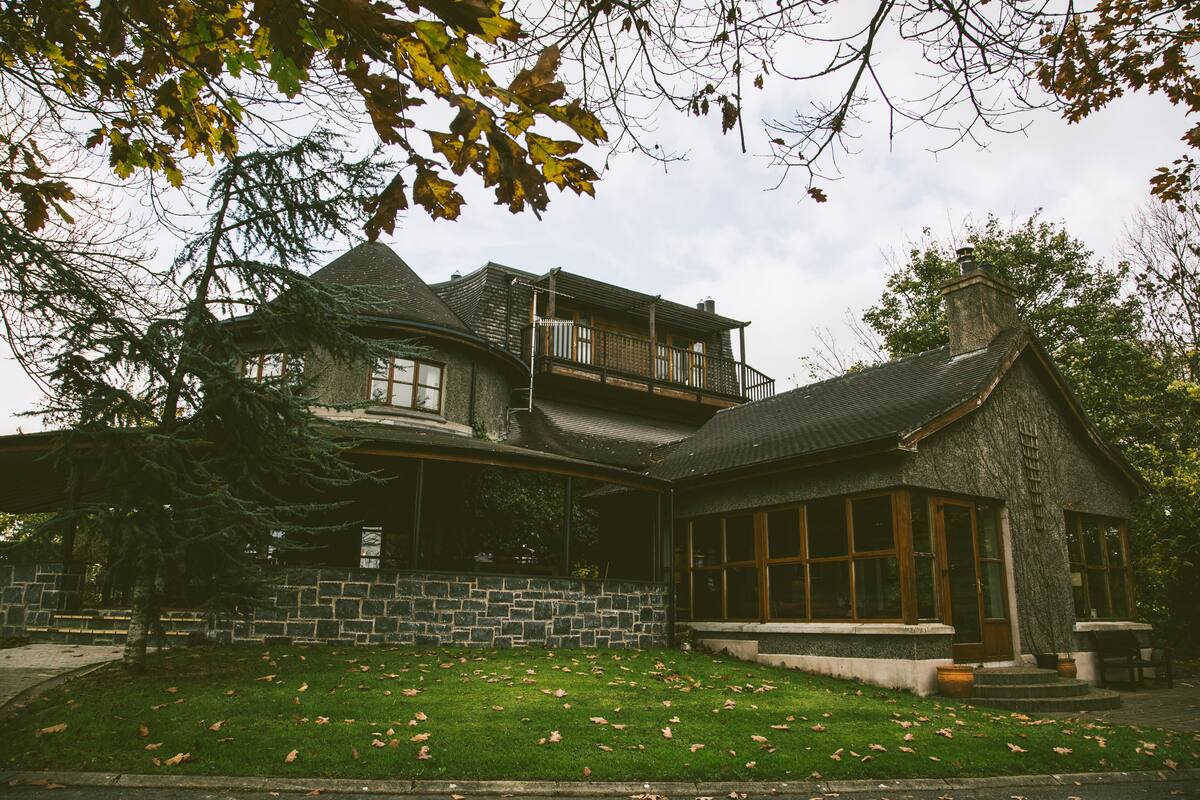 A two-story house with a stone facade, a balcony, and a well-maintained lawn.