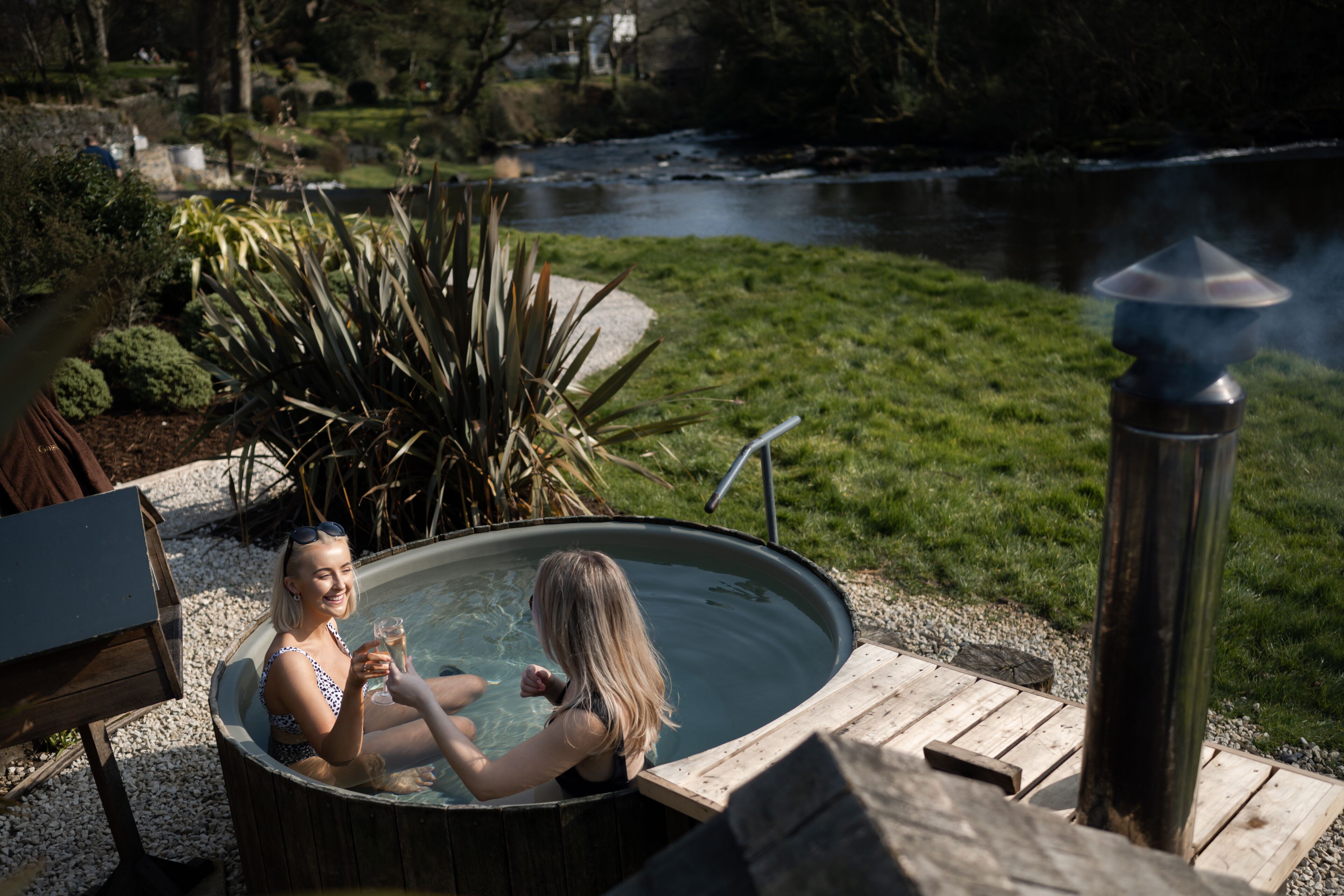 A hot tub with a view of a river and greenery.
