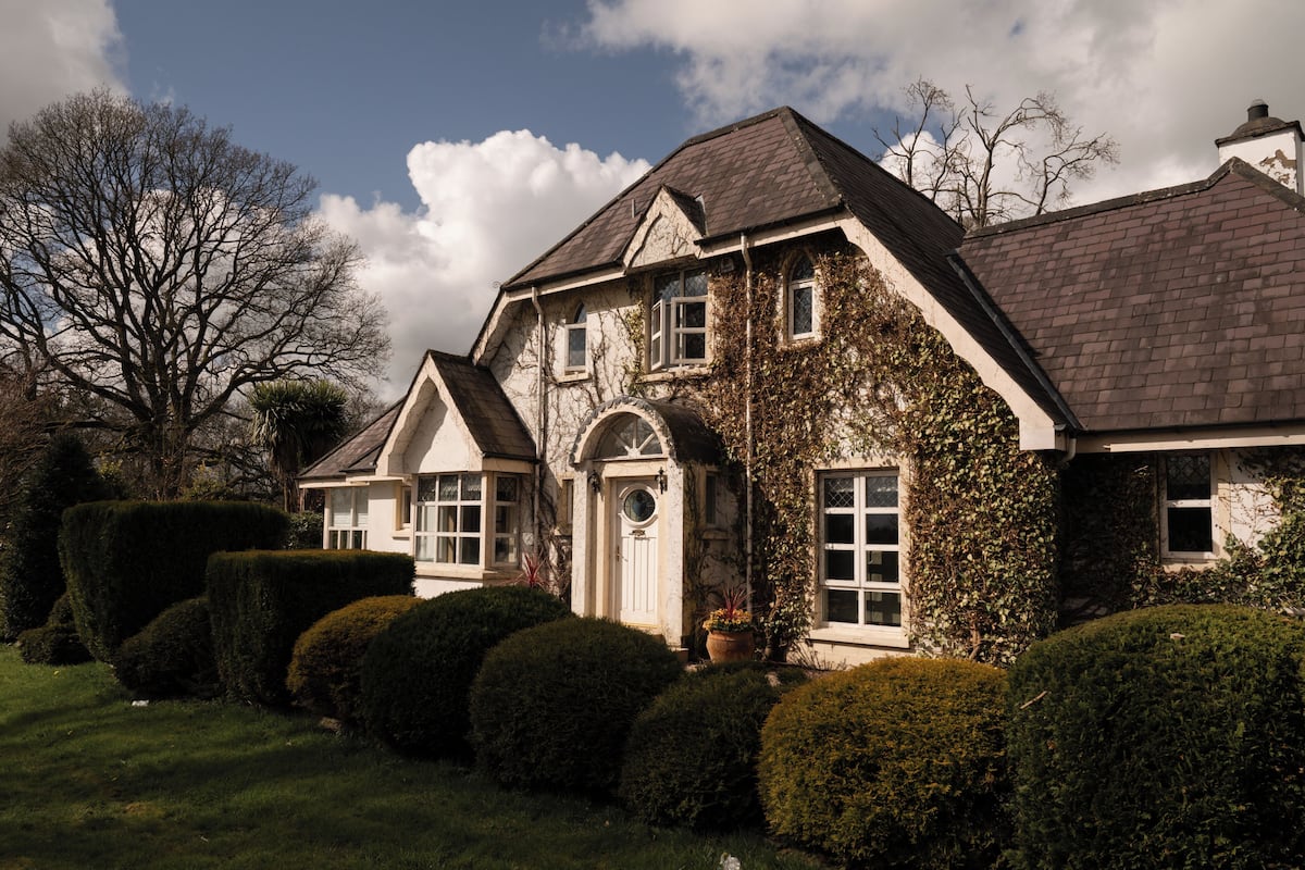 A two-story house with a gabled roof, a front entrance with a door, and a large window.