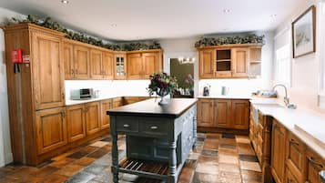 A kitchen with wooden cabinets, a central island, and a stone tile floor.