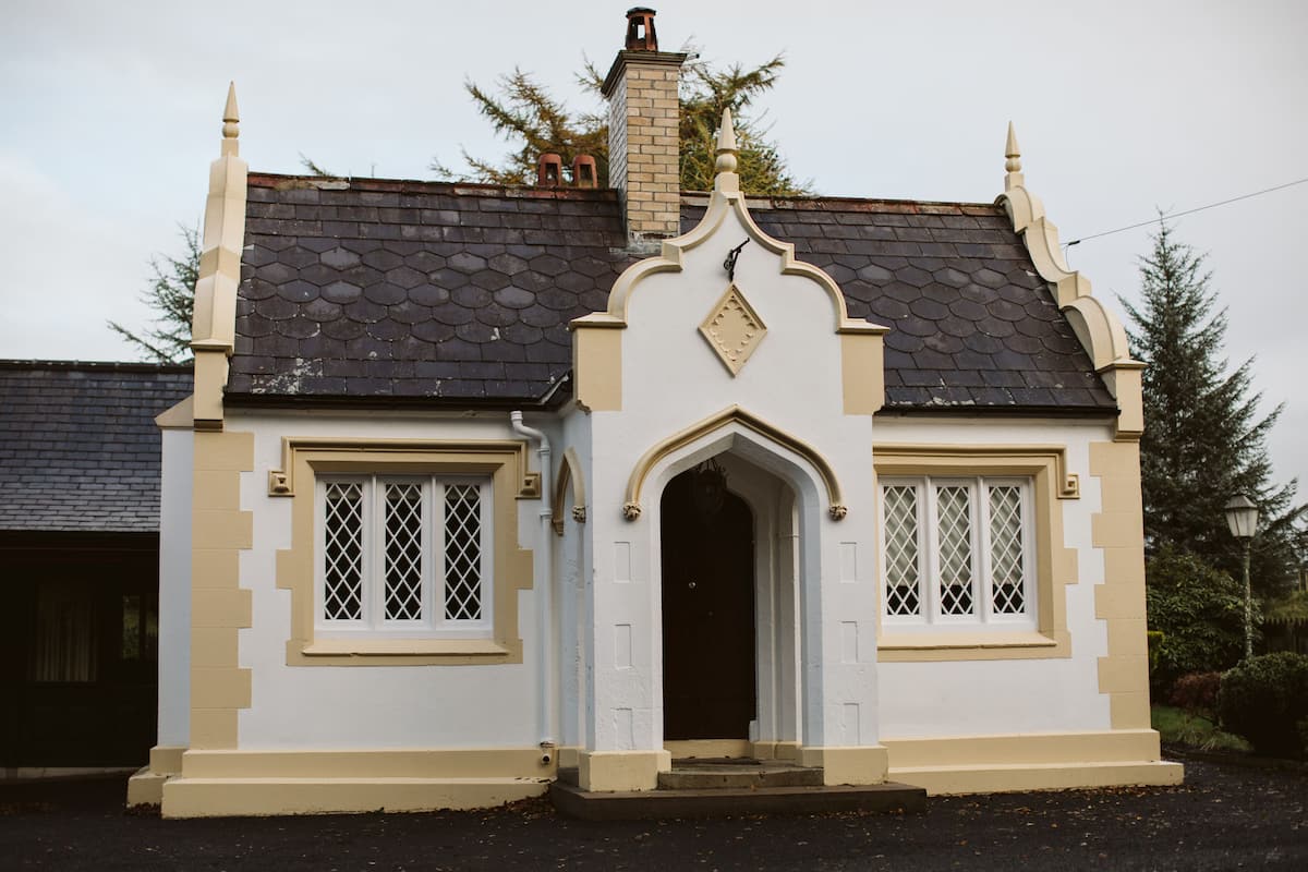 A traditional house with a steeply pitched roof, a central entrance with an arch, and two symmetrically placed windows with diamond-patterned glass.