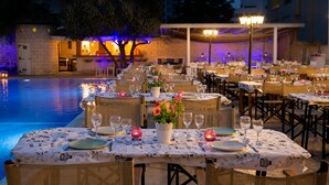 An outdoor dining area with tables set for a meal, overlooking a pool. - Cleopatra Hotel (Nicosia)