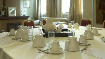 A dining table set with white teapots, cups, and saucers, arranged for a meeting or event.
