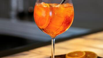 A cocktail glass with ice cubes and a straw, placed on a marble surface.