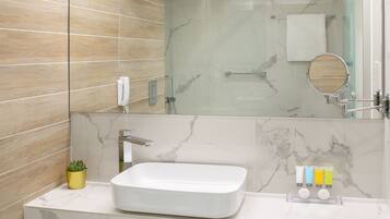 A modern bathroom with a large mirror, a white sink, and a marble backsplash.