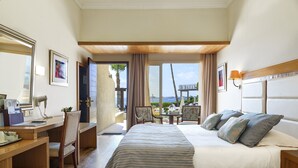 Une chambre d’hôtel avec un lit, un bureau, une chaise et une vue sur la mer.