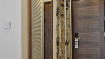 Un pasillo con un espejo grande, puertas de madera y un termostato en la pared.