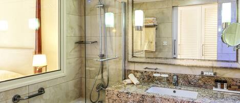 A modern bathroom with a glass-enclosed shower, a bathtub, a granite countertop, a sink, and a large mirror.